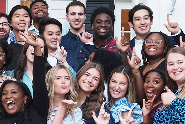 Students smiling and holding up J sign.
