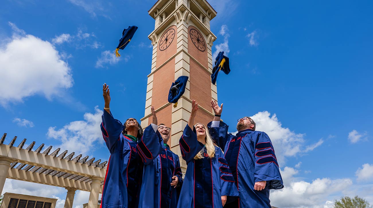 Students throwing up their graduate caps in front of Moulton Tower