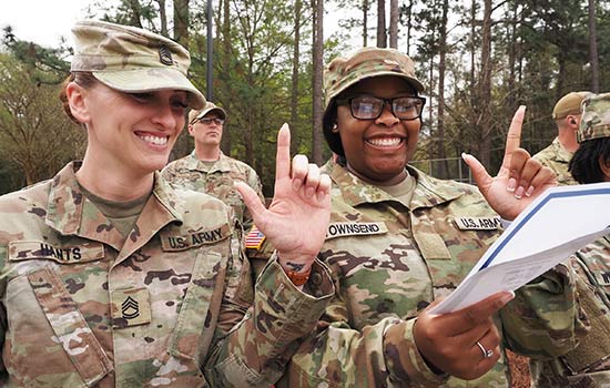 Military students holding up J sign for Jaguars smiling.